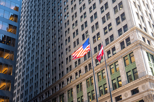 New York City, NY, USA - September 17, 2015: Manhattan, low angle view of a skyscraper at Broadway Liberty, Manhattan casting an interesting shadow, with the American flag.