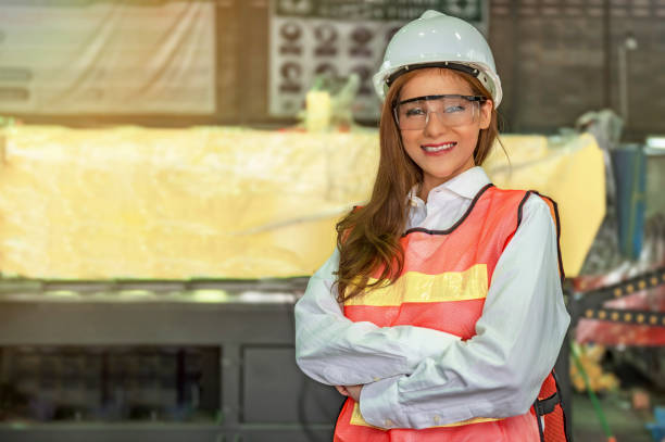 Female industrial engineer smilling with blurred machine background in factory stock photo