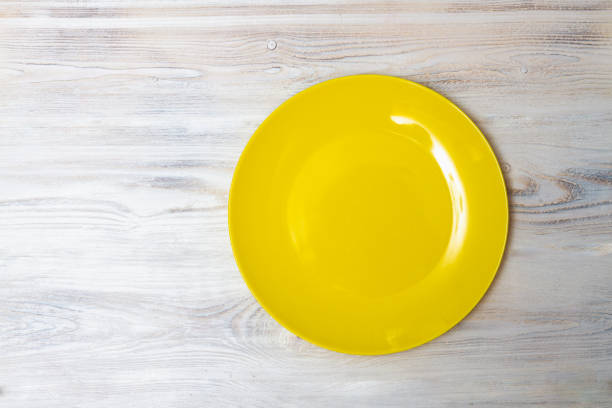 istock A yellow plate on a white wooden table. Copy space 1302742859