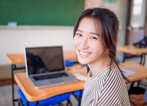 happy asian Student girl  using  laptop in classroom