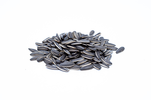 A pile of black sunflower seeds on a white background