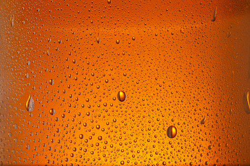 Condensation on  Drinking glass - glass bottle. Ice Cold Beer glass With Water Drops  Orange backgrounds