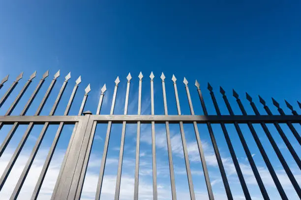 Photo of Wrought Iron Gate with Sharp Points on Blue Sky with Clouds