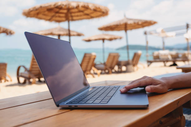 istock a woman working and touching on laptop touchpad on the beach 1302754575