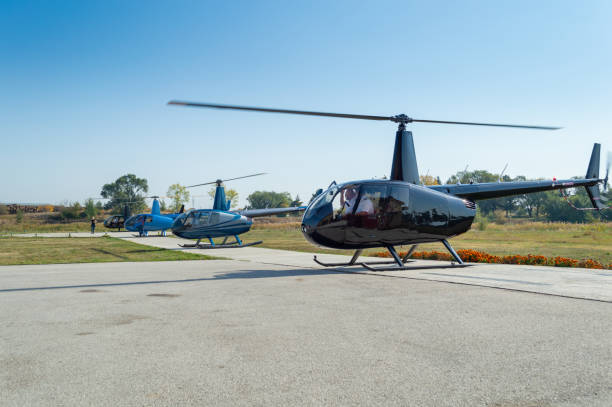 Helicopters landed in a row on helipad Helicopters landed next to each other on helipad, pilots in cockpits helicopter modern stock pictures, royalty-free photos & images