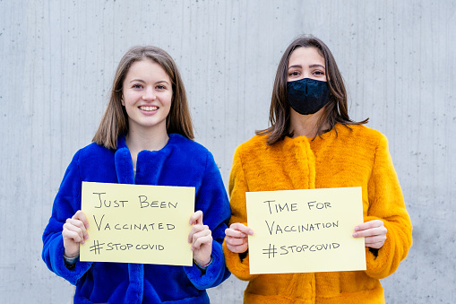Time for vaccination, two young woman encouraging to vaccinate ourself to stop the spread of covid19, optimistic and positive thinking about the future