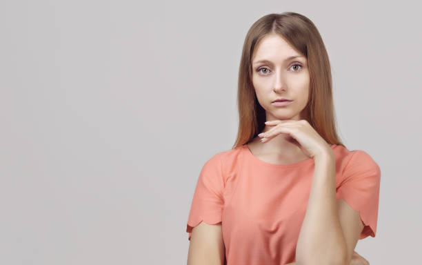 istock Pensive blond girl with thoughtful expression, keeps hand on chin, plans something or makes choice. Place for ad 1302756433