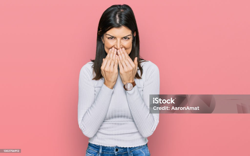 Beautiful brunette woman wearing casual clothes laughing and embarrassed giggle covering mouth with hands, gossip and scandal concept One Woman Only Stock Photo