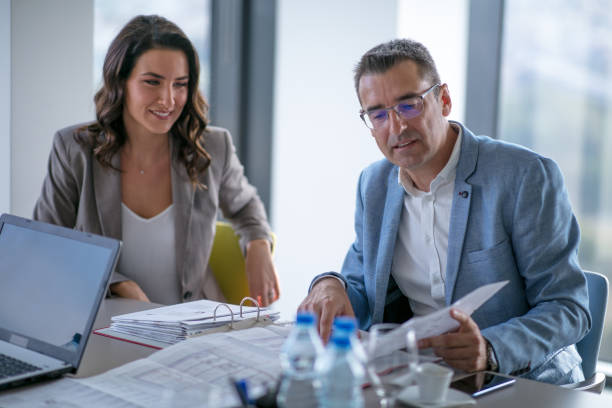 Businessman analyzing financial report, his female colleague looking and smiling stock photo