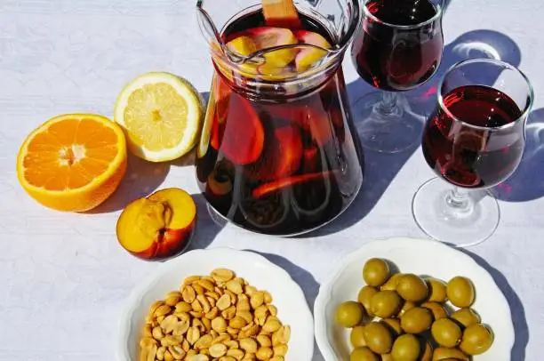 A jug of Sangria with a plate of Olives and Salted peanuts.