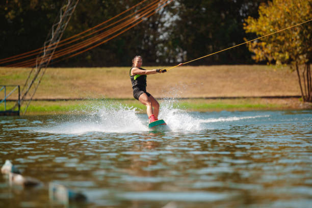 istock Young woman wakeboarding and splashing on water surface 1302760519