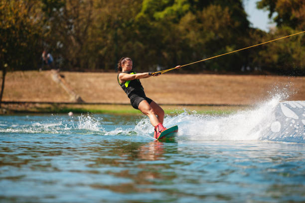 istock Female wakeboarder riding on lake surface pulled by towing rope 1302760540