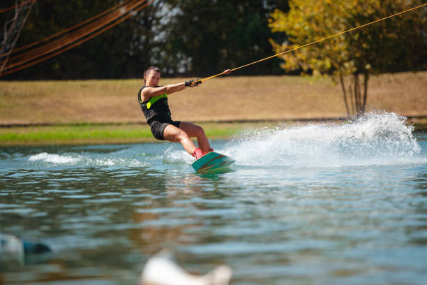 istock Female wakeboarder riding on water surface pulled by towing rope 1302760544
