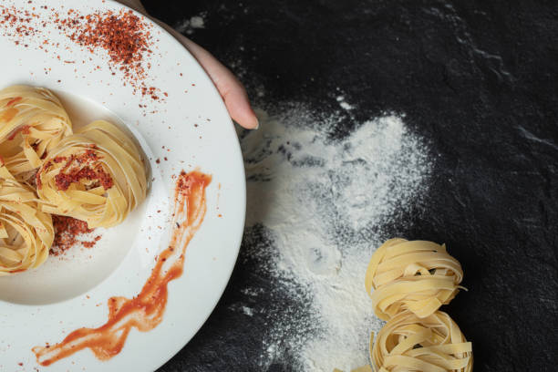 A white plate with uncooked nest noodles with flour