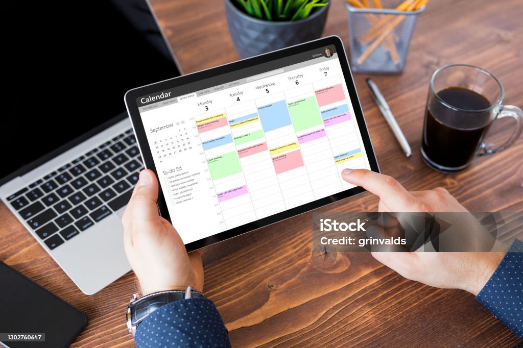 Man using calendar app on tablet at work Man using calendar app on tablet in office Calendar Stock Photo