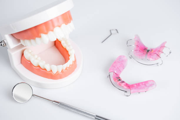 istock Removable orthodontic or orthodontic devices for children with crooked teeth, model teeth and dental mirror on white background. 1302761831
