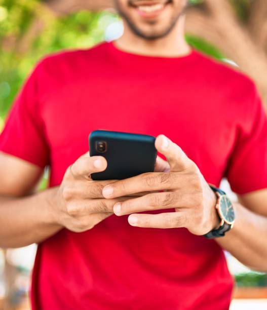 istock Young latin man smiling happy using smartphone walking at the city. 1302761932