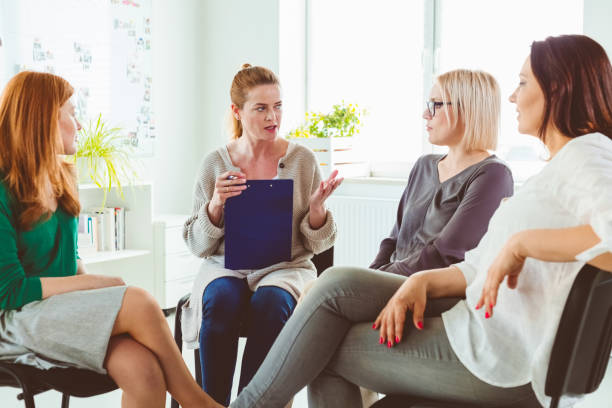 istock Woman discussing experiences with group in session 1302763043