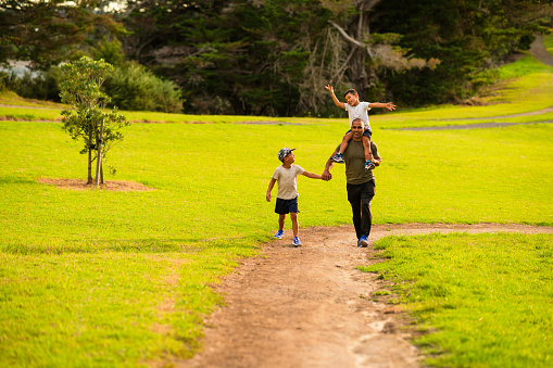 Father with kids enjoying a walk in park on a beautiful summer afternoon in Auckland, New Zealand.