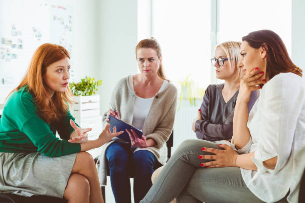 istock Woman discussing experiences with group in session 1302763164