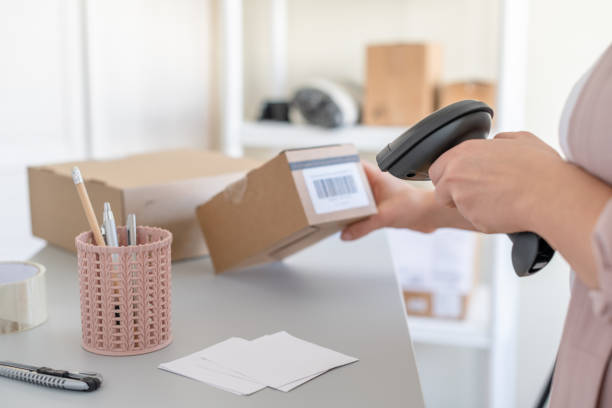 istock Woman employee of post office scanning parcel using barcode scanner to confirm sending customer. Home delivery service. 1302763213