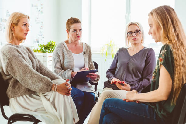 istock Woman discussing experiences with group in session 1302763330