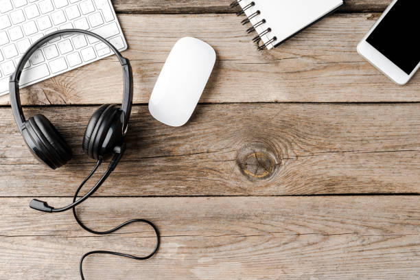 istock Headset and office accessories on wooden table with copyspace. Call center concept 1302763343