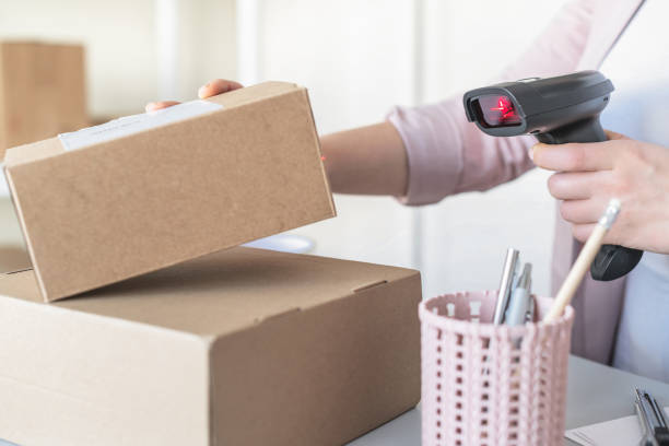 istock Woman employee of post office scanning parcel using barcode scanner to confirm sending customer. Home delivery service. 1302763356