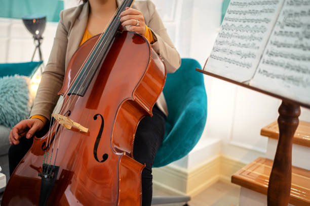 istock Young woman playing violoncello at home 1302764582