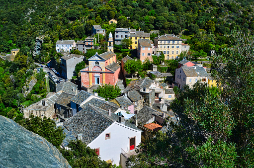 Nonza, France - May 5, 2019. Panoramic view of the village of Nonza in Corsica. the typical and colorful houses of the Corsican villages as well as the village church are visible in the heart of the Mediterranean vegetation.