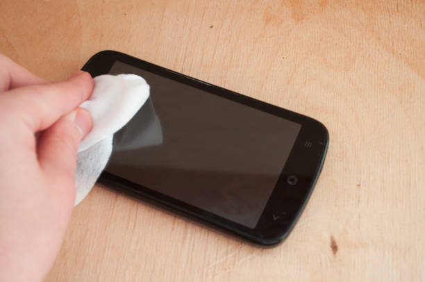 istock Cleaning mobile phone screen with disinfecting wet wipes for clean smartphone preventive wiping for COVID-19 Coronavirus outbreak contamination prevention. 1302768190