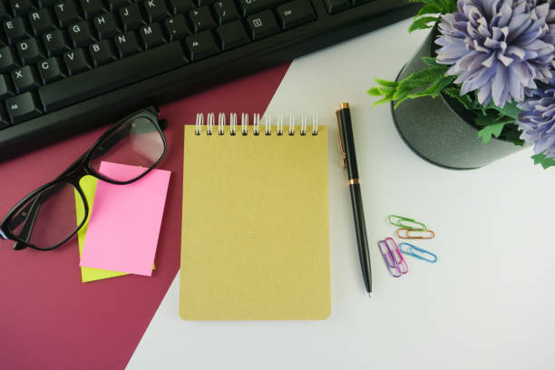 istock Note Pad, Pen, Sticky Notes, Paper Clips and Computer Keyboard and Potted Plant on Multi Colored Background 1302771888