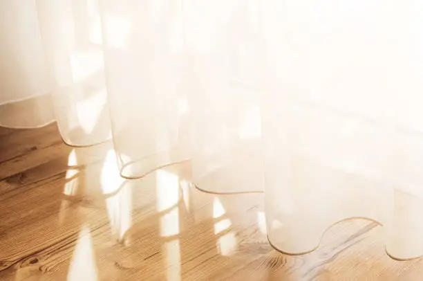 Photo of Transparent white curtain tulle from an open window. Sunny day