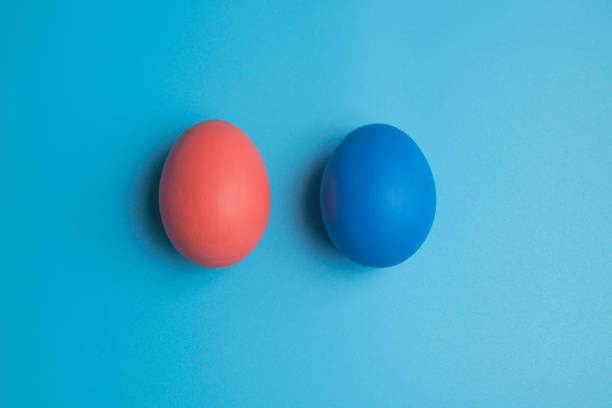 istock Pink and blue eggs. Eggs on a blue background. Two colored chicken eggs. 1302775447