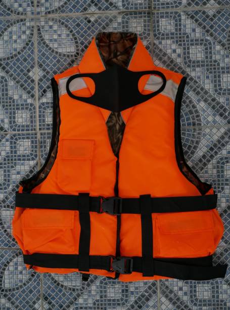 eine neoprenschwarze schutzmaske auf einer orangefarbenen schwimmweste auf dem boden des pools. einhaltung der sicherheitsmaßnahmen für coronaviren beim schwimmen im pool - life jacket isolated life belt nobody stock-fotos und bilder