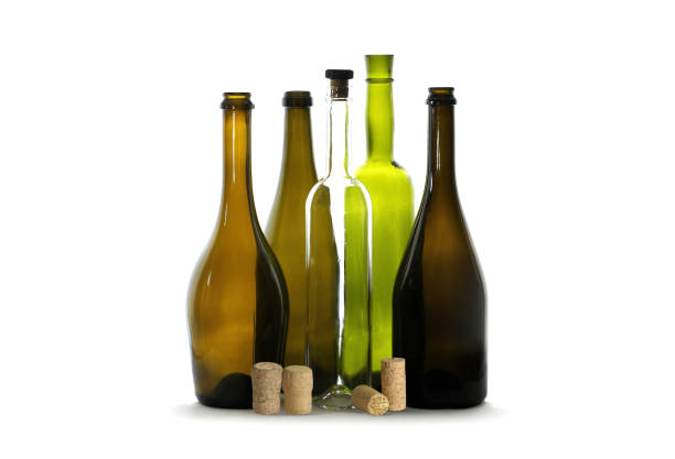 natura morta con bottiglia di vino trasparente con tappo di vino e bottiglia di vino verde tra bottiglie di vino vuote marroni isolate su bianco - grape white grape green muscat grape foto e immagini stock