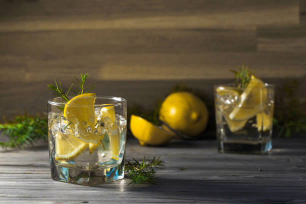 istock Cocktail with lemon slices and juniper branch on a old wooden table. 1302779105