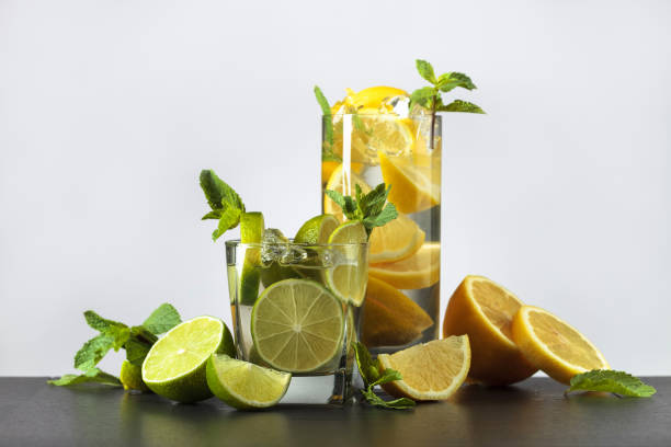 istock Cocktails with lime, lemon, ice and mint on a black table. 1302779119
