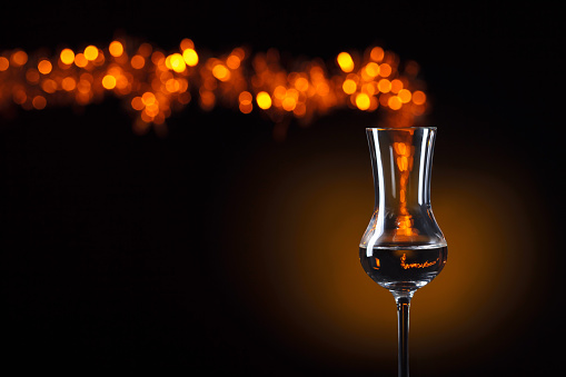 Glass of brandy with natural bokeh on a dark background. Conceptual image of the theme of strong alcoholic drinks. Copy space.