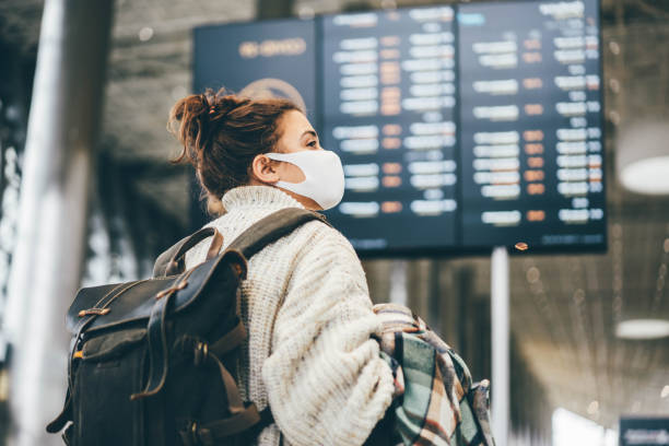 frau in schutzmaske blick auf informationen am flughafen. - timeboard stock-fotos und bilder