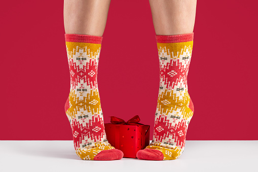 Close-up of colorful soft socks. Concept of comfort and relaxation of female feet, red background. Gift in box.