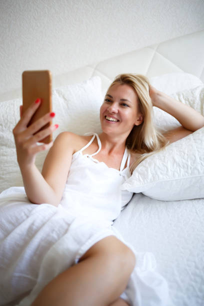 istock young woman on a white bed is working talking by videoconference 1302782068