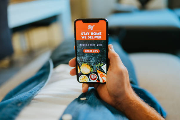 istock Man ordering food online using mobile app at home 1302782336