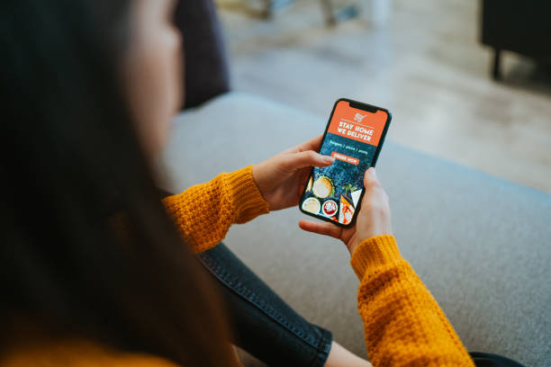 istock Woman ordering food online using mobile app at home 1302782346