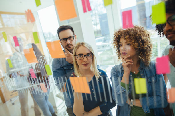 istock Business team brainstorming in front of glass wall with adhesive notes 1302782880