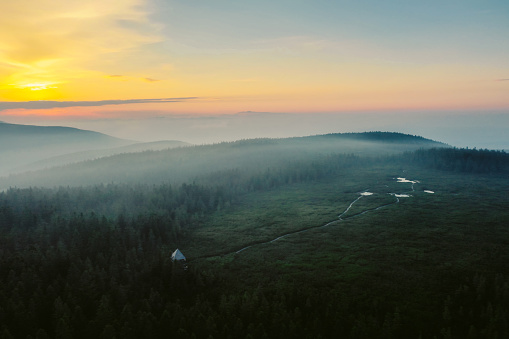 Scenic view of rural landscape covered with fog during sunset