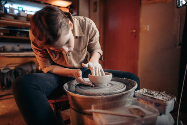 istock Young woman shaping bowl on potter's wheel 1302783884