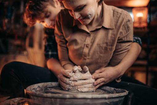 Close up of couple working in pottery wheel at workshop