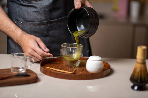 istock Man making matcha green tea with traditional accessories closeup 1302783954