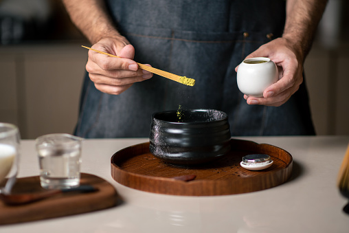 Man making matcha green tea with traditional accessories closeup
